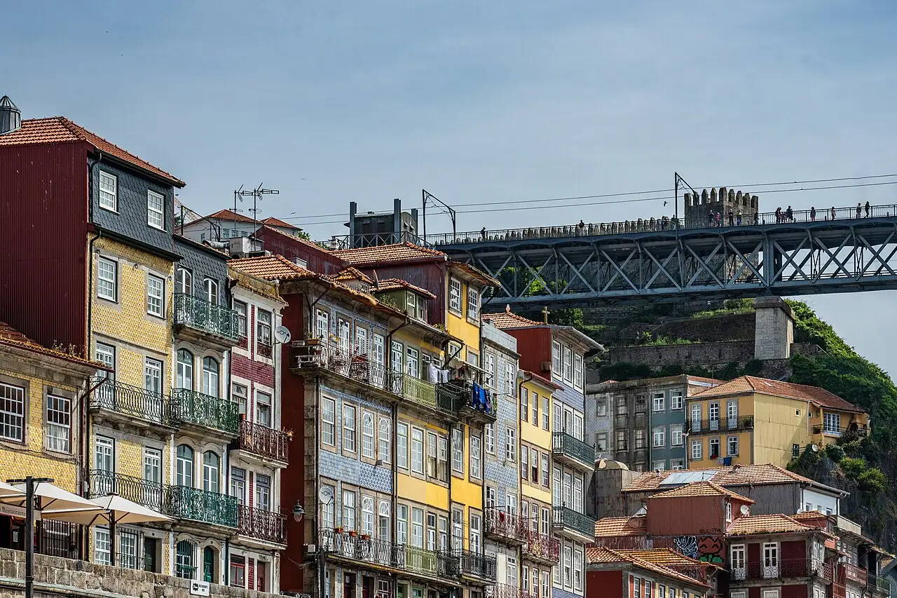 Colourful tiled and painted houses with iron balconies on the Ribeira waterfront in Porto, with the Dom Luís I bridge above them