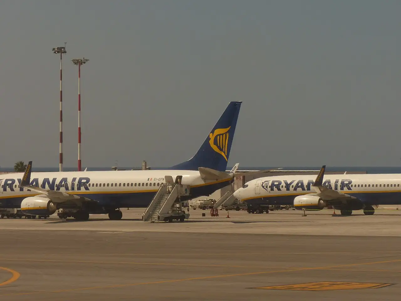 Two Ryanair Boeing 737 aircraft parked with boarding stairs on the apron at Palermo Falcone Borsellino Airport in Sicily, with the sea behind