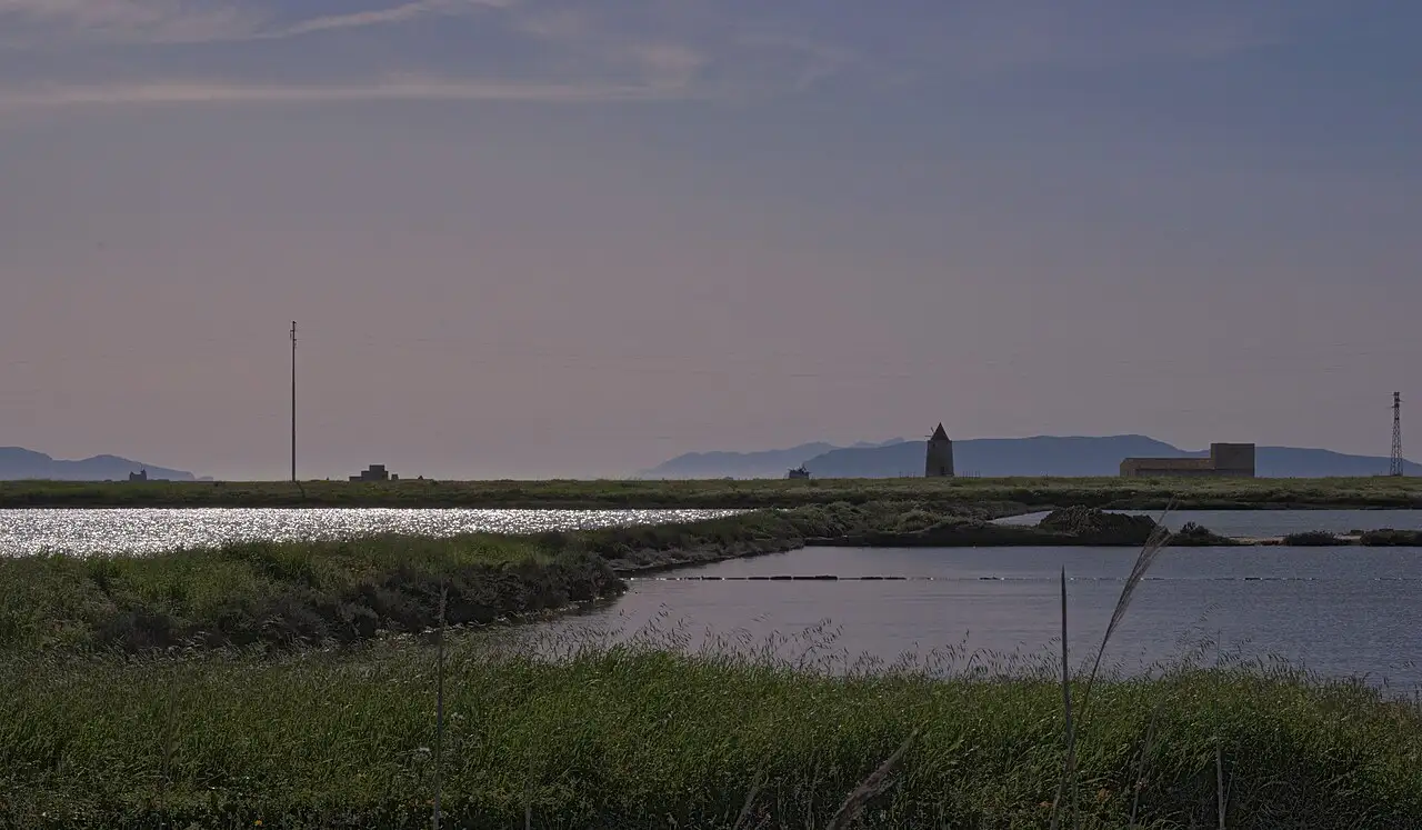 Salt pans between Trapani and Marsala in western Sicily with a stone windmill, shallow pools and green marsh, near Trapani-Birgi airport
